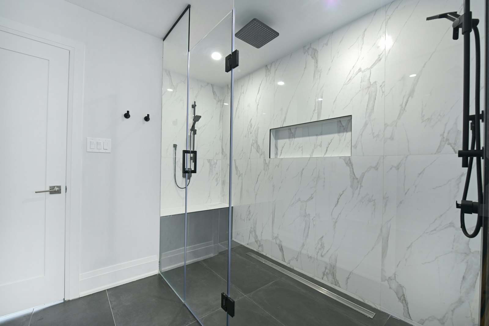 Baño reformado con ducha a ras de suelo, mampara de cristal y hornacina