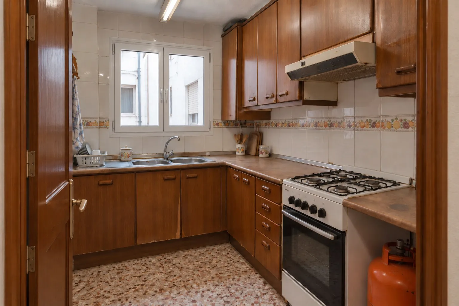 Cocina con muebles de madera y cocina de gas en un piso de Los Álamos, Torremolinos, antes de la reforma