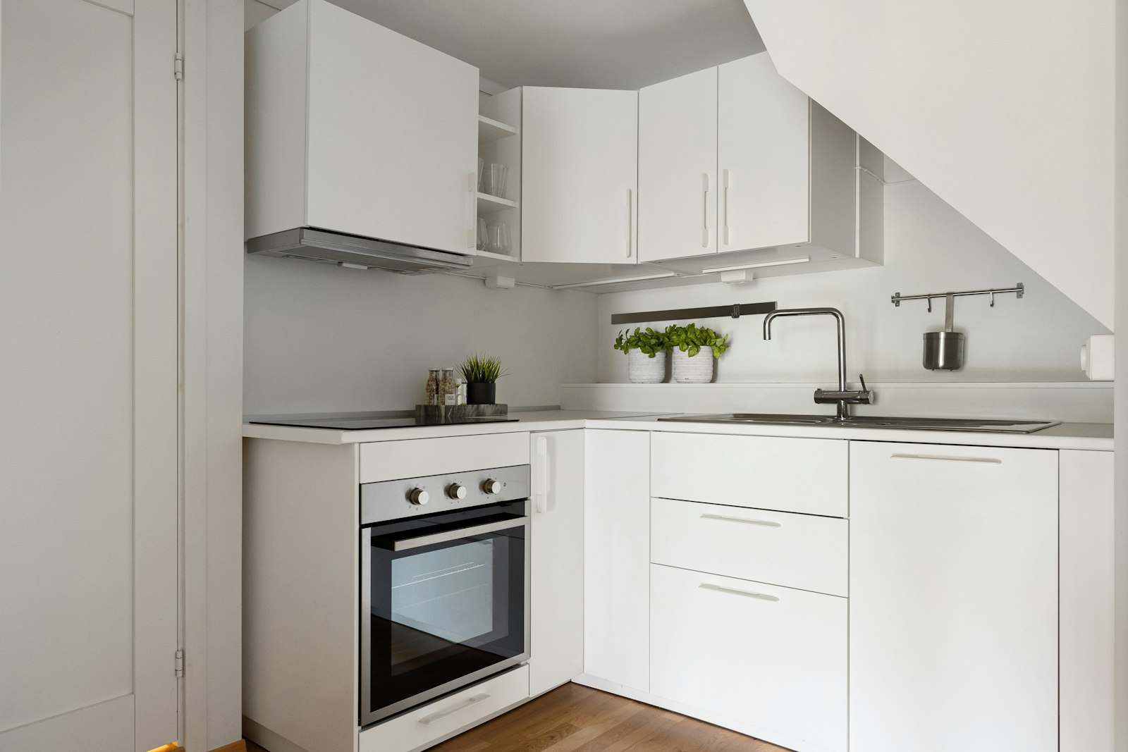 Cocina pequeña en L con muebles blancos y horno integrado